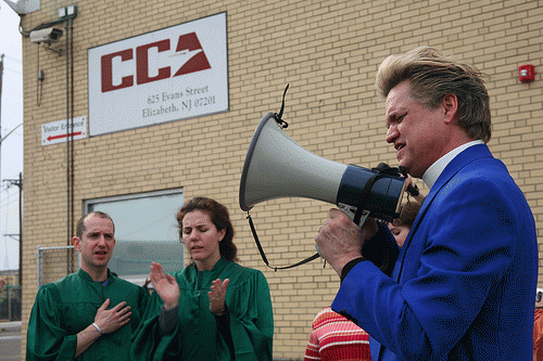 Reverend Billy Talent and the Church of Life After Shopping protest the Correction Centers of America building, a commercial immigrant detention center (privately-owned prison), From ImagesAttr