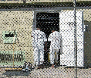 Two detainees in white stand in the doorway of their bay in Camp 4.