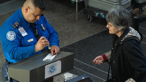 A US Transportation Security Administration (TSA) agent checks the identification and boarding pass of a passenger as she passes through security in the terminal at Ronald Reagan Washington National Airport in Arlington, Virginia, From ImagesAttr