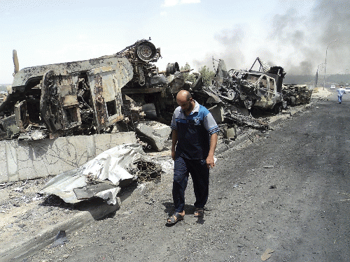 Man walks past near remains of burnt vehicles belonging to Iraqi security forces in the northern Iraq city of Mosul, June 13, 2014., From ImagesAttr