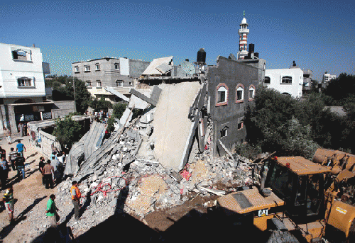 Palestinians inspect a home destroyed in an Israeli air strike in the central Gaza Strip on 9 July., From ImagesAttr