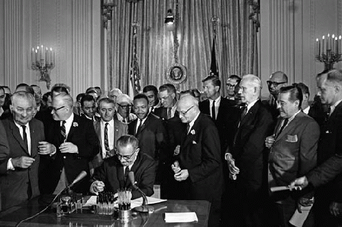 Lyndon B. Johnson signing the 1964 Civil Rights Act as Martin Luther King, Jr., and others look on, Washington, D.C., July 2, 1964; Lyndon B. Johnson Library and Museum, From ImagesAttr