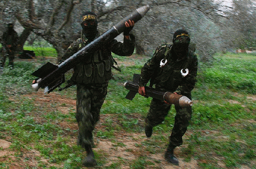 Masked Palestinian militants from Islamic Jihad run with homemade rockets to put in place before later firing them into Israel on the outskirts of Gaza City, From ImagesAttr