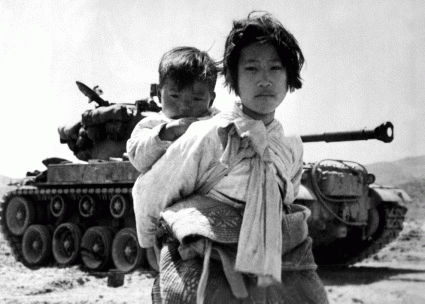 With her brother on her back a war weary Korean girl tiredly trudges by a stalled M-26 tank, at Haengju, Korea. June 9, 1951., From ImagesAttr