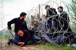 Syrian refugees cross into Hungary underneath the border fence