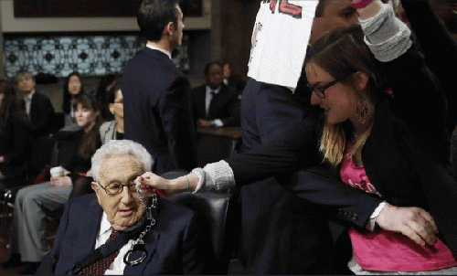 Alli McCracken, Co-director of the peace group CODEPINK, dangles a pair of handcuffs in front of former Secretary of State Henry during a protest at a Senate hearing in January 2015., From ImagesAttr