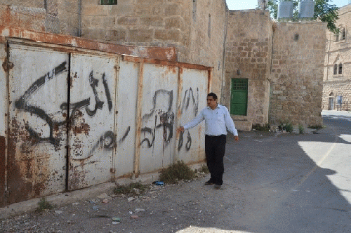 Badee Dwaik, of the non-government organisation Human Rights Defenders, points out grafitti on a wall in occupied Hebron, H2, that says 