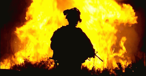 A U.S. soldier watches flames rise into the night sky after setting canal vegetation ablaze in Tahwilla, Iraq, July 30, 2008. Iraqis opposed to the U.S. occupation were said to be using the canal's thick vegetation to plant bombs under the cover of darkne