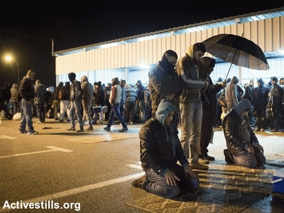 Palestinian workers pray after crossing Eyal checkpoint, between the West Bank city of Qalqilya and Israel., From ImagesAttr