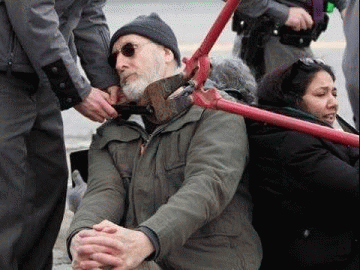 Police use bolt cutters to remove a lock around James Cromwell's neck during a protest at a New York power plant.