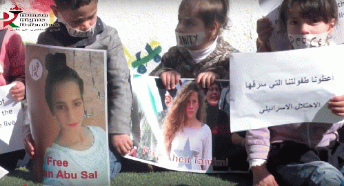 Still from video, Kindergarteners hold posters of incarcerated children Razan Abu Sal and  Ahed Tamimi.