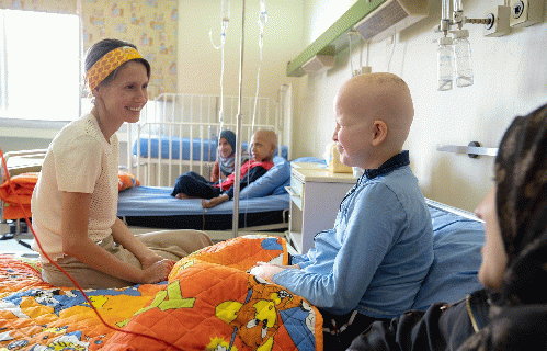 Asma Assad while visiting cancer-stricken children at a hospital in the city of Harasta in Damascus in 2018.)