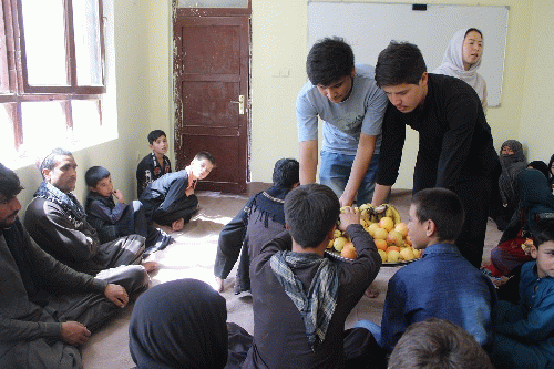 Habib (standing, left) serves fruit at a meeting for parents at a 