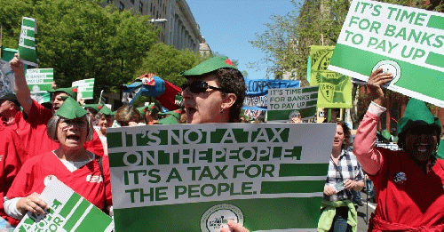 Demonstrators hold signs in support of a financial transactions tax (FTT), also known as a Robin Hood tax. Demonstrators hold signs in support of a financial transactions tax (FTT), also known as a Robin Hood tax.