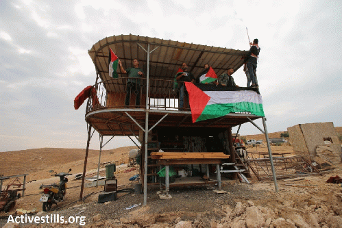 Activists raise the Palestinian flag at the illegal settlement outpost. Photo: Activestills.org, From Uploaded