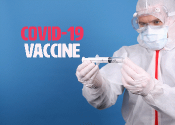 From live.staticflickr.com: Doctor in face mask holding syringe with Covid-19 Vaccine text  