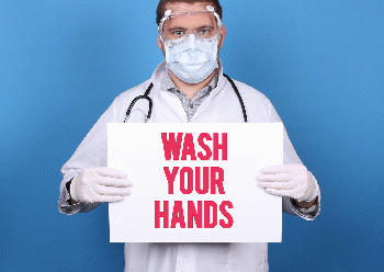 Wash Your Hands. Doctor holding message sign for COVID-19 Pandemic at blue background